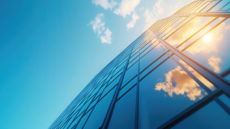 A tall building with a clear blue sky and a large cloud in the background