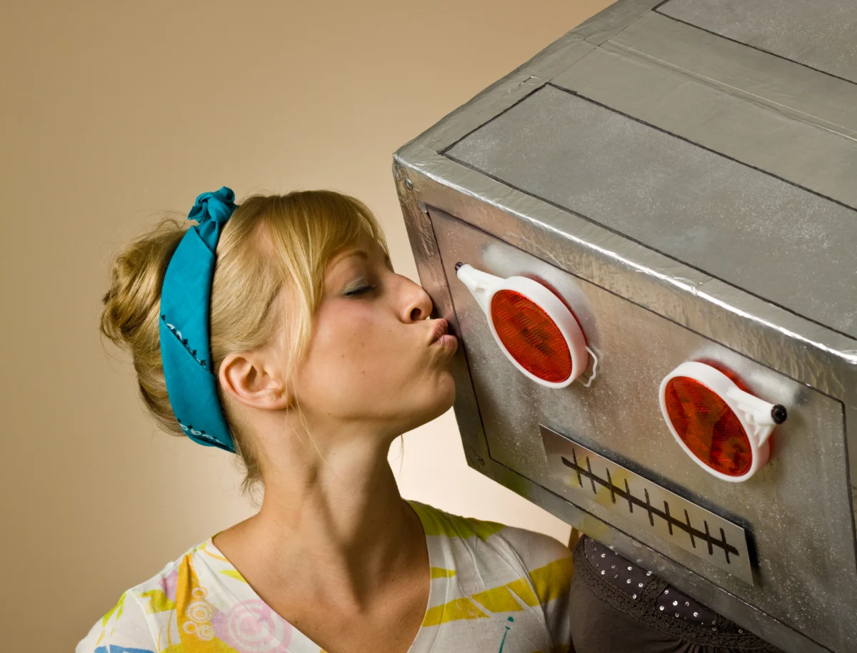 Close-up of woman in striped shirt kissing robot